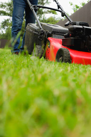 Professional JC Landscape Service gardener mowing the lawn in front of a house